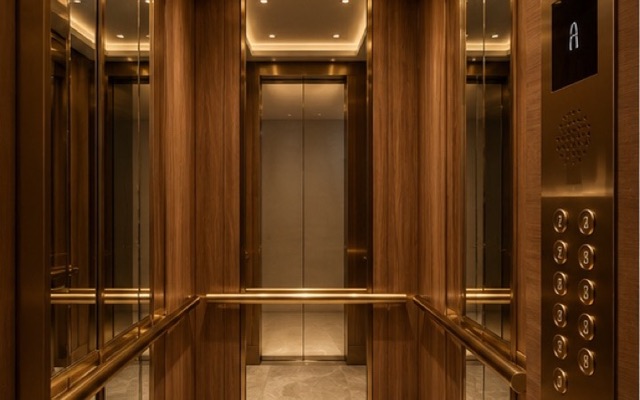 Interior de cabine de elevador com acabamento em madeira e latão.